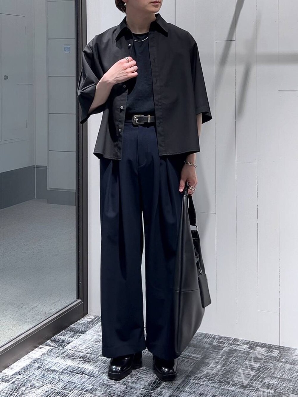 ブラック系のドレスシューズ、ブラック系のトートバッグ、ブラック系のTシャツ/カットソーを着用したメンズの春コーディネートの2枚目の写真