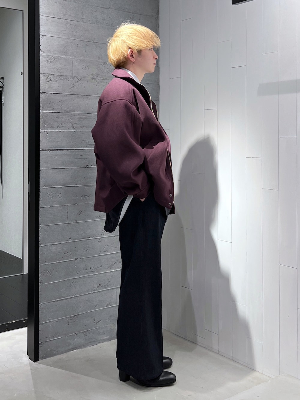 レッド系のブルゾン、ブルー系のデニムパンツ、ブラック系のブーツを着用したメンズの秋コーディネートの4枚目の写真