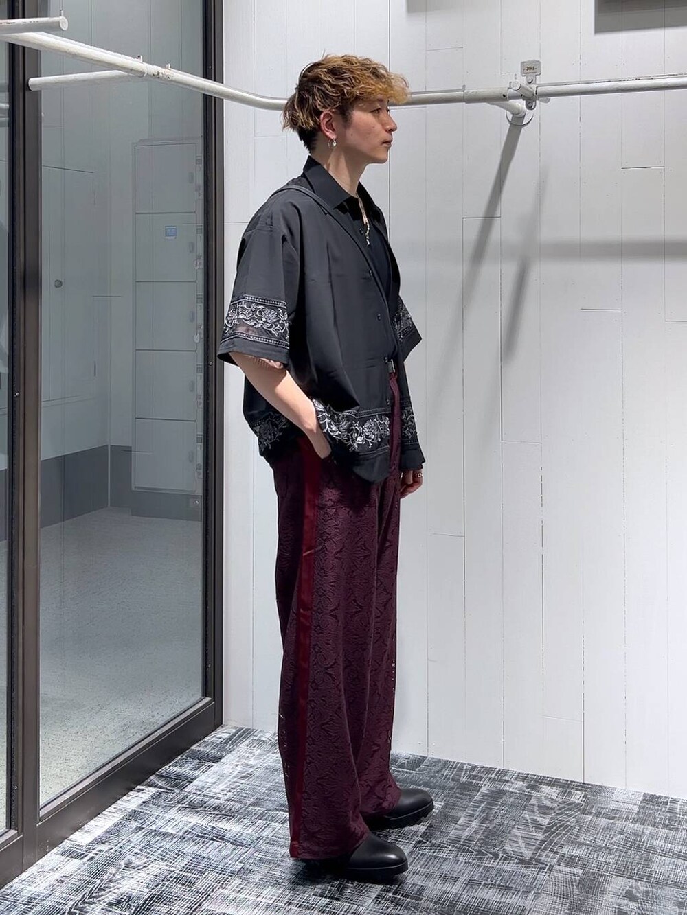 ブラック系のドレスシューズ、レッド系のその他パンツ、ブラック系のTシャツ/カットソーを着用したメンズの夏コーディネートの2枚目の写真