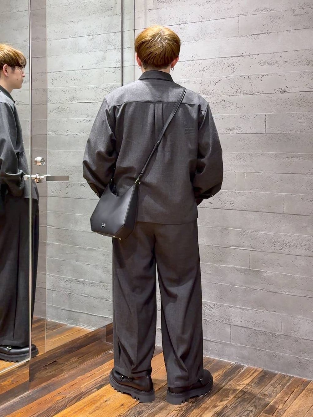 ブラック系のドレスシューズ、ブラック系のスラックス、ブラック系のショルダーバッグを着用したメンズの春コーディネートの3枚目の写真