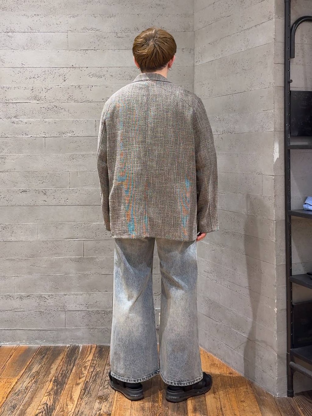 ブラック系のサンダル、グレー系のテーラードジャケット、ブルー系のデニムパンツを着用したメンズの春コーディネートの3枚目の写真