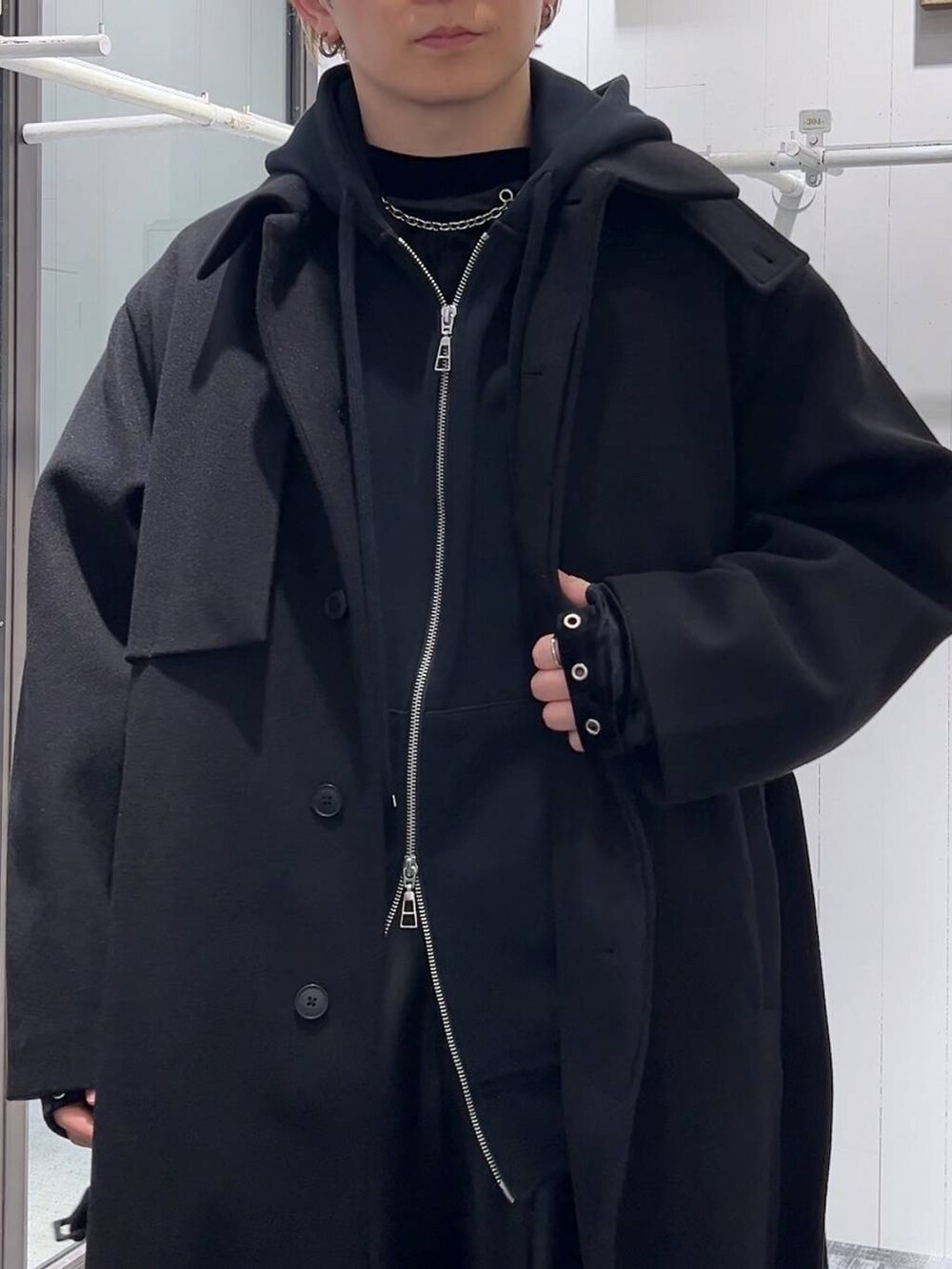 ブラック系のステンカラーコート、ブラック系のその他パンツ、ブラック系のパーカーを着用したメンズの冬コーディネートの5枚目の写真