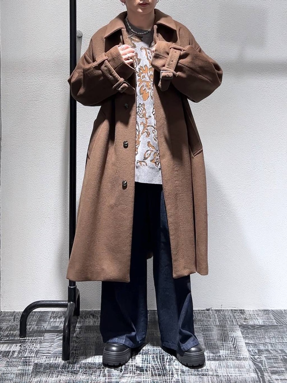 ブルー系のデニムパンツ、グレー系のニット/セーター、ブラウン系のステンカラーコートを着用したメンズの冬コーディネートの2枚目の写真