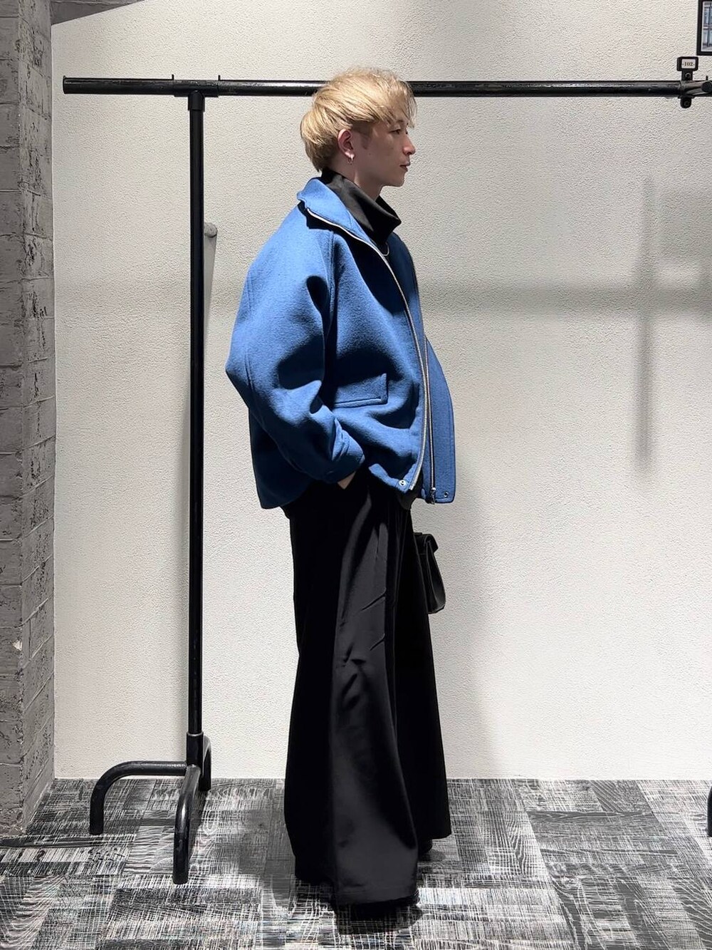 ブルー系のブルゾン、ブラック系のスラックス、ブラック系のショルダーバッグを着用したメンズの秋コーディネートの2枚目の写真