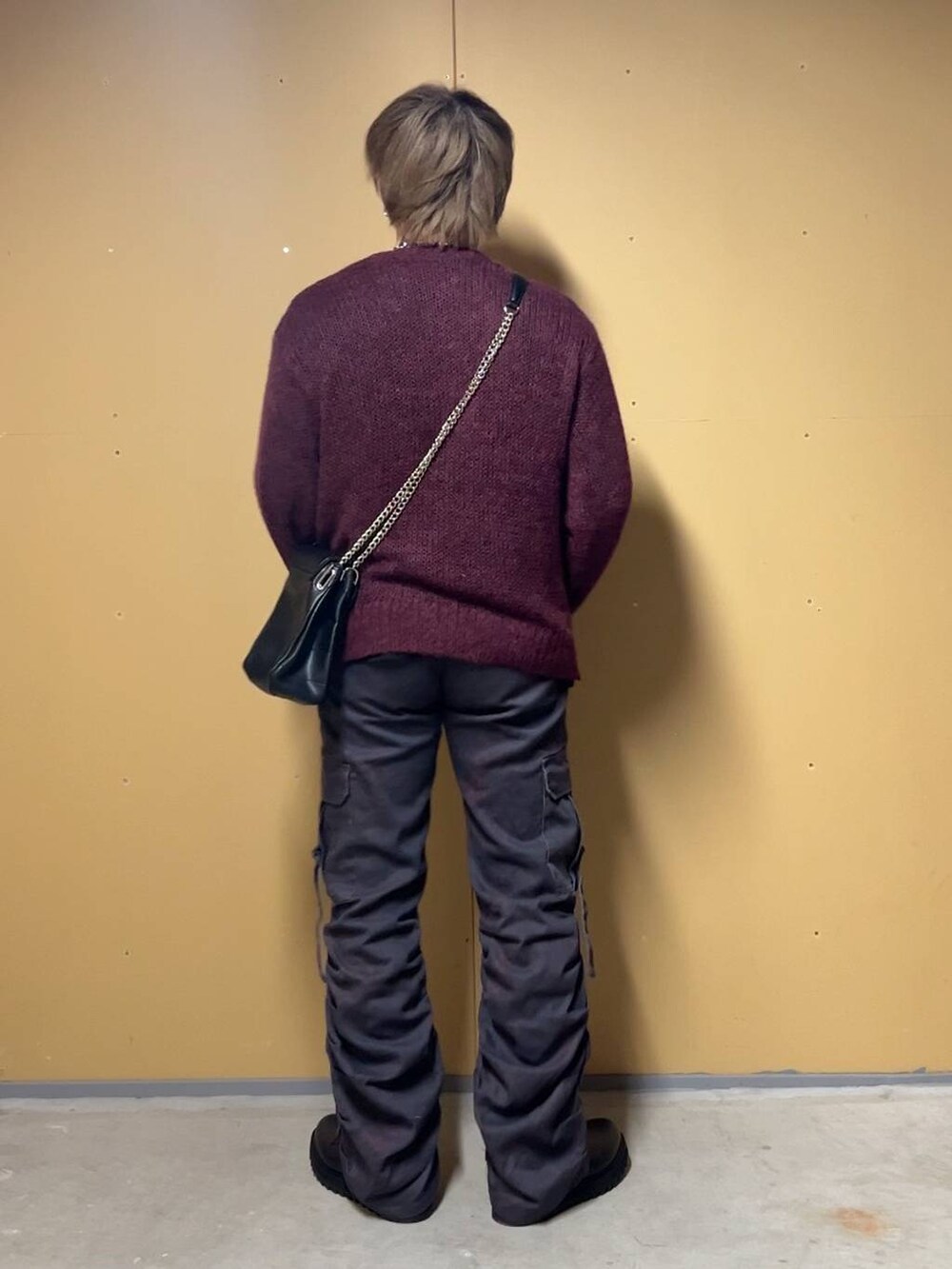 ブラック系のドレスシューズ、ブラック系のショルダーバッグ、レッド系のニット/セーターを着用したメンズの春コーディネートの3枚目の写真