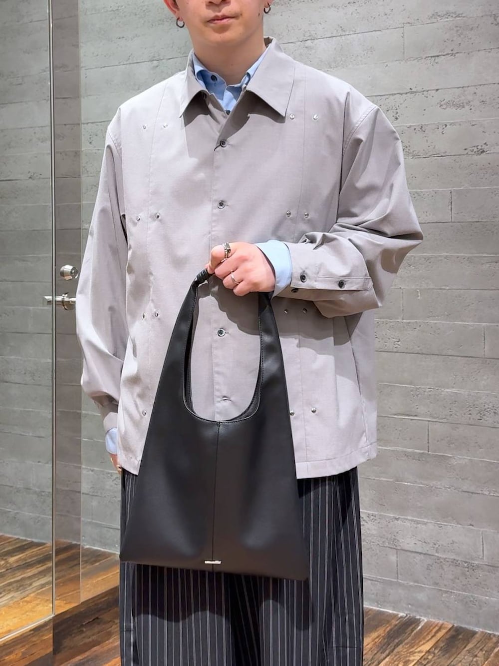 ブラック系のトートバッグ、ブラック系のブーツ、ブラック系のスラックスを着用したメンズの春コーディネートの5枚目の写真