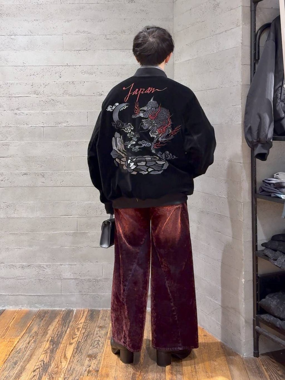 ブラック系のブーツ、レッド系のデニムパンツ、ブラック系のショルダーバッグを着用したメンズの冬コーディネートの3枚目の写真