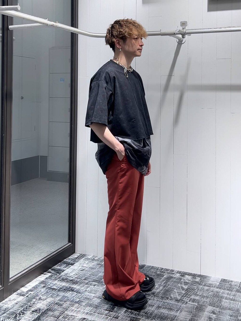 ブラック系のサンダル、オレンジ系のスラックス、ブラック系のTシャツ/カットソーを着用したメンズの夏コーディネートの3枚目の写真