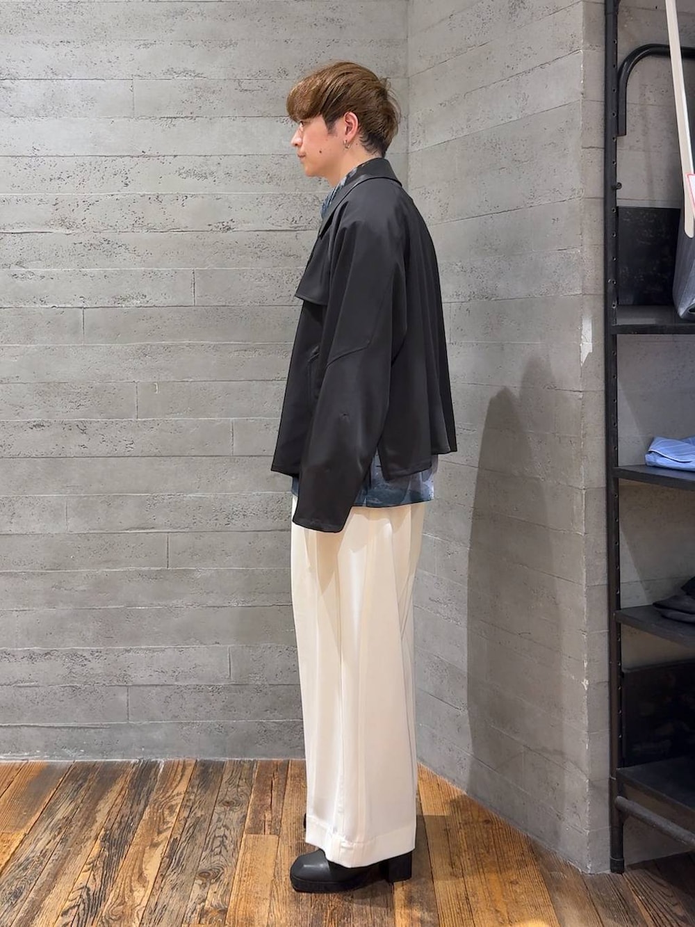 ブラック系のブーツ、ホワイト系のスラックス、ブラック系のブルゾンを着用したメンズの春コーディネートの4枚目の写真