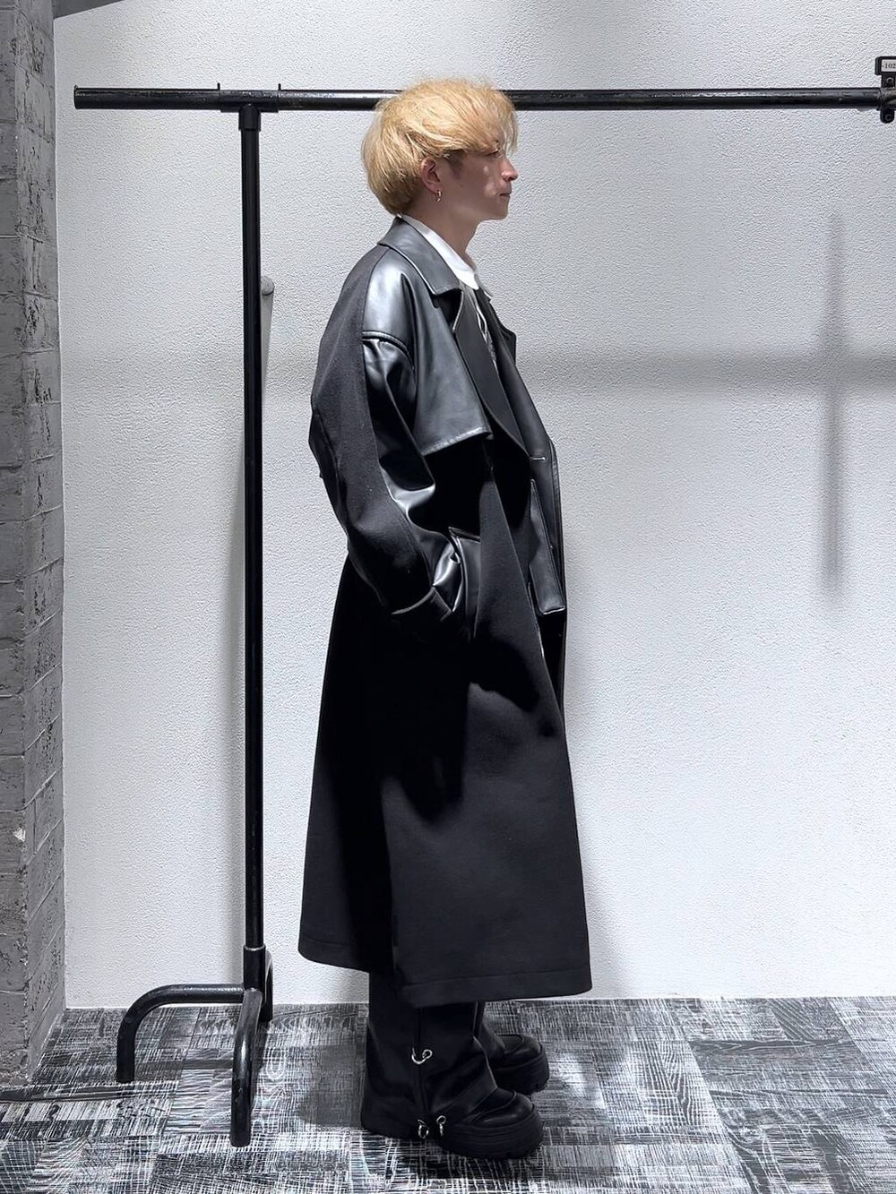 ブラック系のトレンチコート、ブラック系のショルダーバッグ、ブラック系のブーツを着用したメンズの秋コーディネートの4枚目の写真