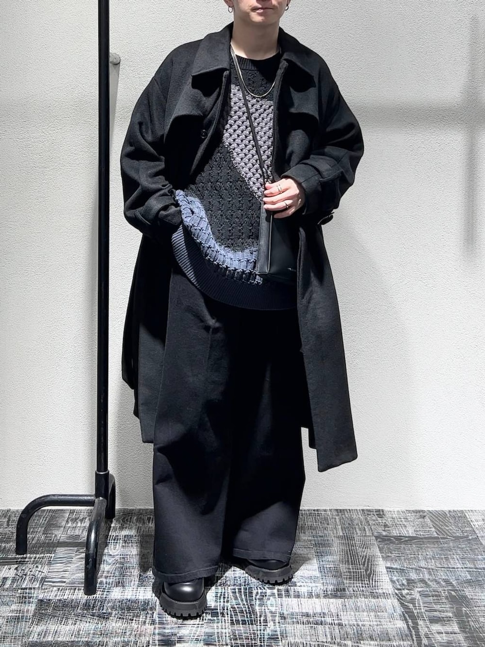 ブラック系のデニムパンツ、ブラック系のステンカラーコート、ブラック系のショルダーバッグを着用したメンズの秋コーディネートの2枚目の写真