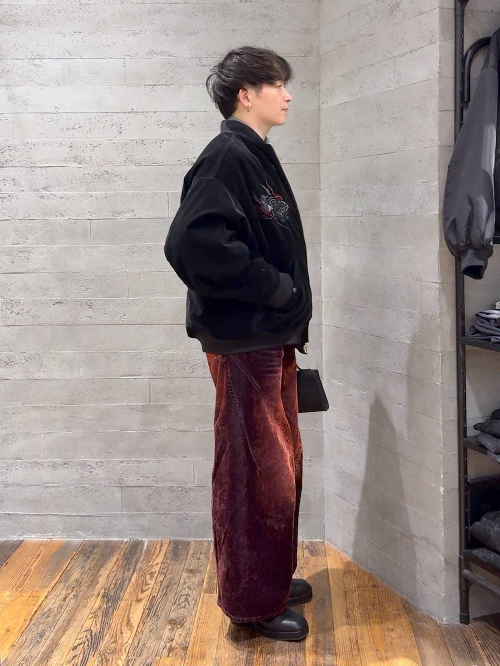 ブラック系のブーツ、レッド系のデニムパンツ、ブラック系のショルダーバッグを着用したメンズの冬コーディネートの2枚目の写真