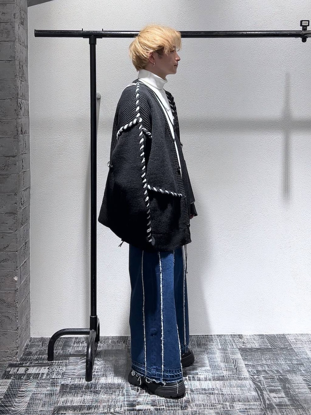 ブルー系のデニムパンツ、ブラック系のショルダーバッグ、ホワイト系のスウェットを着用したメンズの冬コーディネートの3枚目の写真