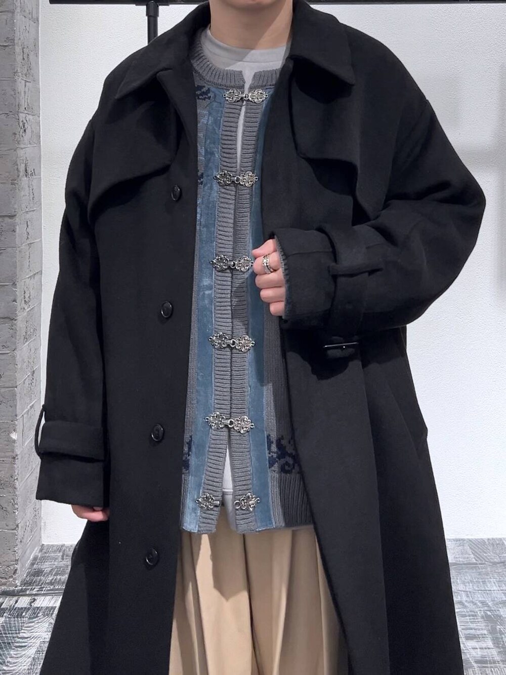 ブラック系のステンカラーコート、ブラック系のドレスシューズ、グレー系のスウェットを着用したメンズの冬コーディネートの5枚目の写真