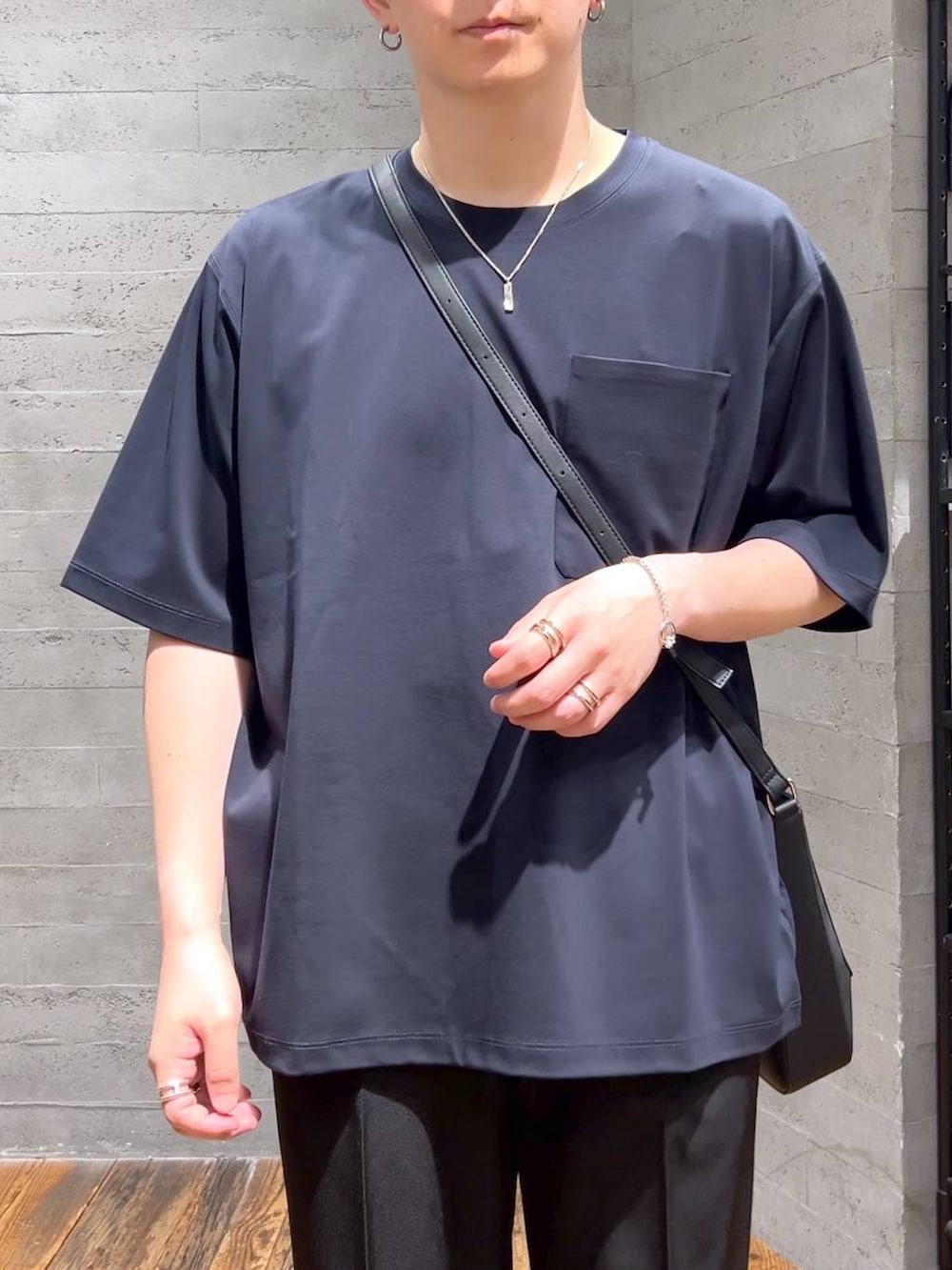 ブラック系のショルダーバッグ、ブルー系のTシャツ/カットソー、ブラック系のドレスシューズを着用したメンズの夏コーディネートの5枚目の写真