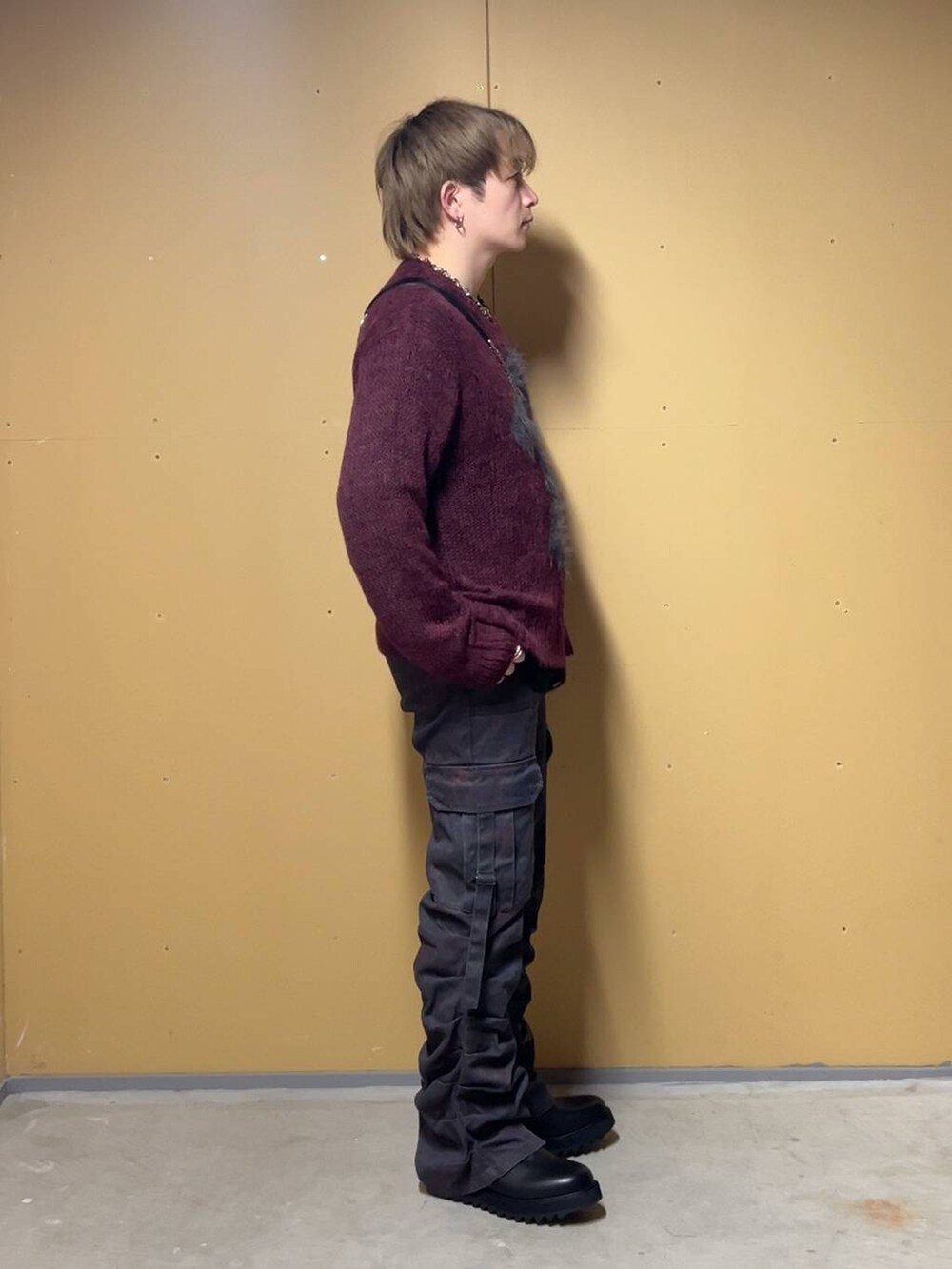 ブラック系のドレスシューズ、ブラック系のショルダーバッグ、レッド系のニット/セーターを着用したメンズの春コーディネートの2枚目の写真