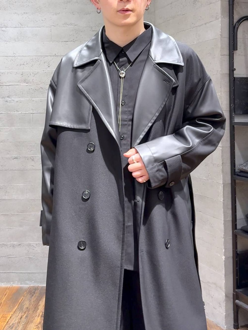 ブラック系のトレンチコート、ブラック系のブーツ、シルバー系のネックレスを着用したメンズの秋コーディネートの5枚目の写真