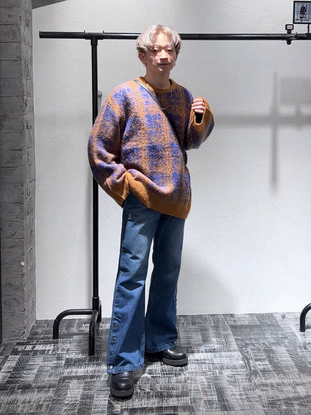 ブルー系のデニムパンツ、ブラック系のショルダーバッグ、オレンジ系のニット/セーターを着用したメンズの秋コーディネートの2枚目の写真