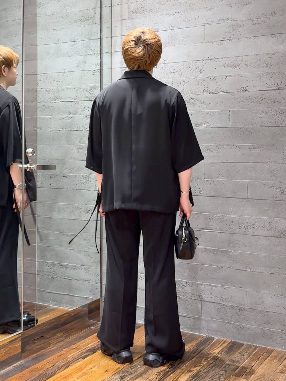 ブラック系のスラックス、ブラック系のサンダル、ホワイト系のTシャツ/カットソーを着用したメンズの夏コーディネートの3枚目の写真