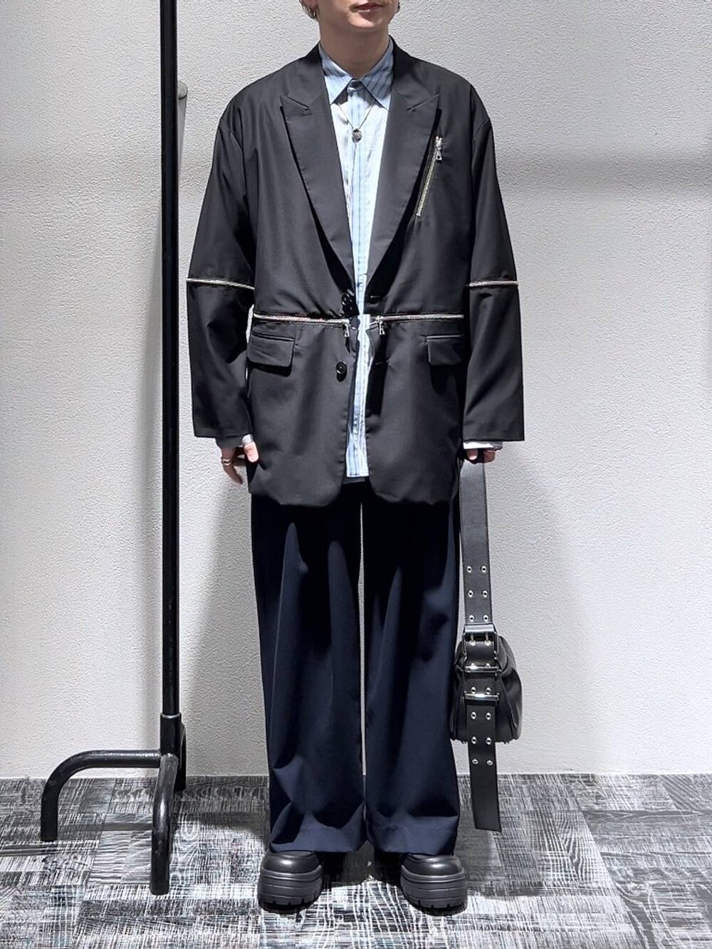 ブラック系のスニーカー、ブルー系のスラックス、ブラック系のショルダーバッグを着用したメンズの春コーディネートの2枚目の写真