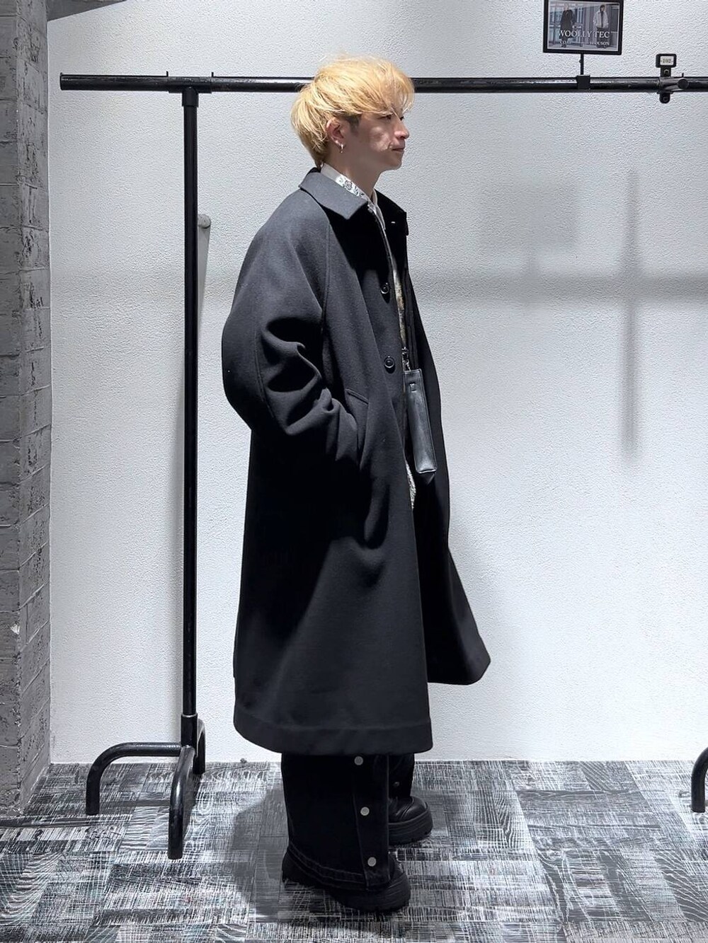 ブラック系のステンカラーコート、ブラック系のショルダーバッグ、グレー系のカーディガン/ボレロを着用したメンズの冬コーディネートの3枚目の写真