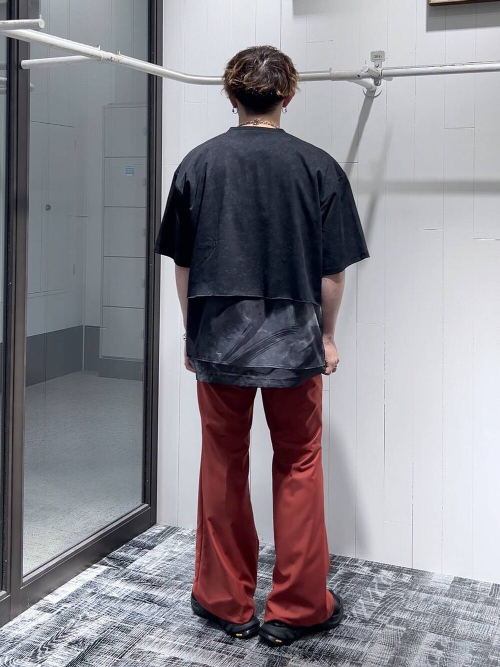 ブラック系のサンダル、オレンジ系のスラックス、ブラック系のTシャツ/カットソーを着用したメンズの夏コーディネートの2枚目の写真