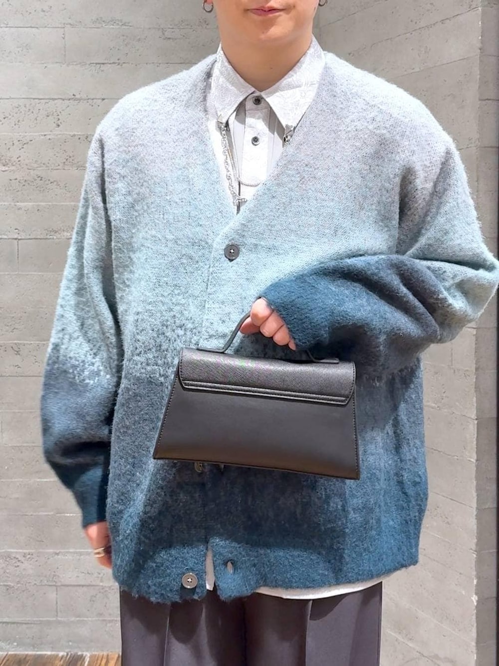 グリーン系のカーディガン/ボレロ、ブラック系のスニーカー、グレー系のスラックスを着用したメンズの冬コーディネートの5枚目の写真