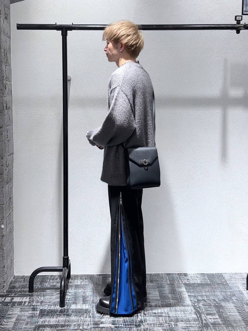 ブラック系のショルダーバッグ、ブラック系のブーツ、ブルー系のスラックスを着用したメンズの秋コーディネートの3枚目の写真