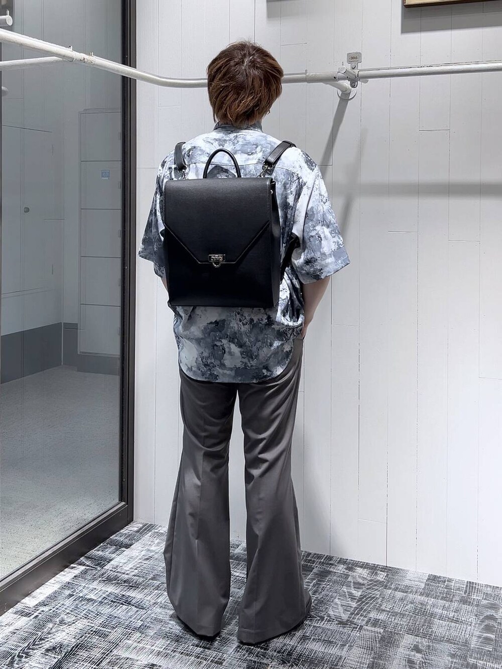 ブラック系のドレスシューズ、ブラック系のショルダーバッグ、グレー系のスラックスを着用したメンズの春コーディネートの4枚目の写真