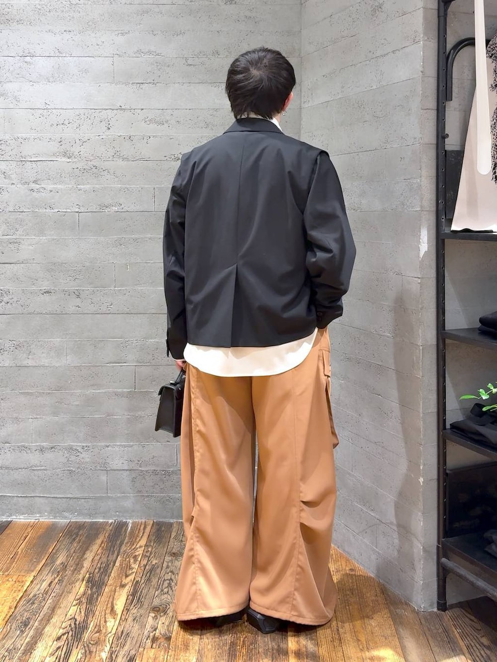 ブラック系のスニーカー、ブラック系のハンドバッグ、ブラック系のテーラードジャケットを着用したメンズの冬コーディネートの3枚目の写真