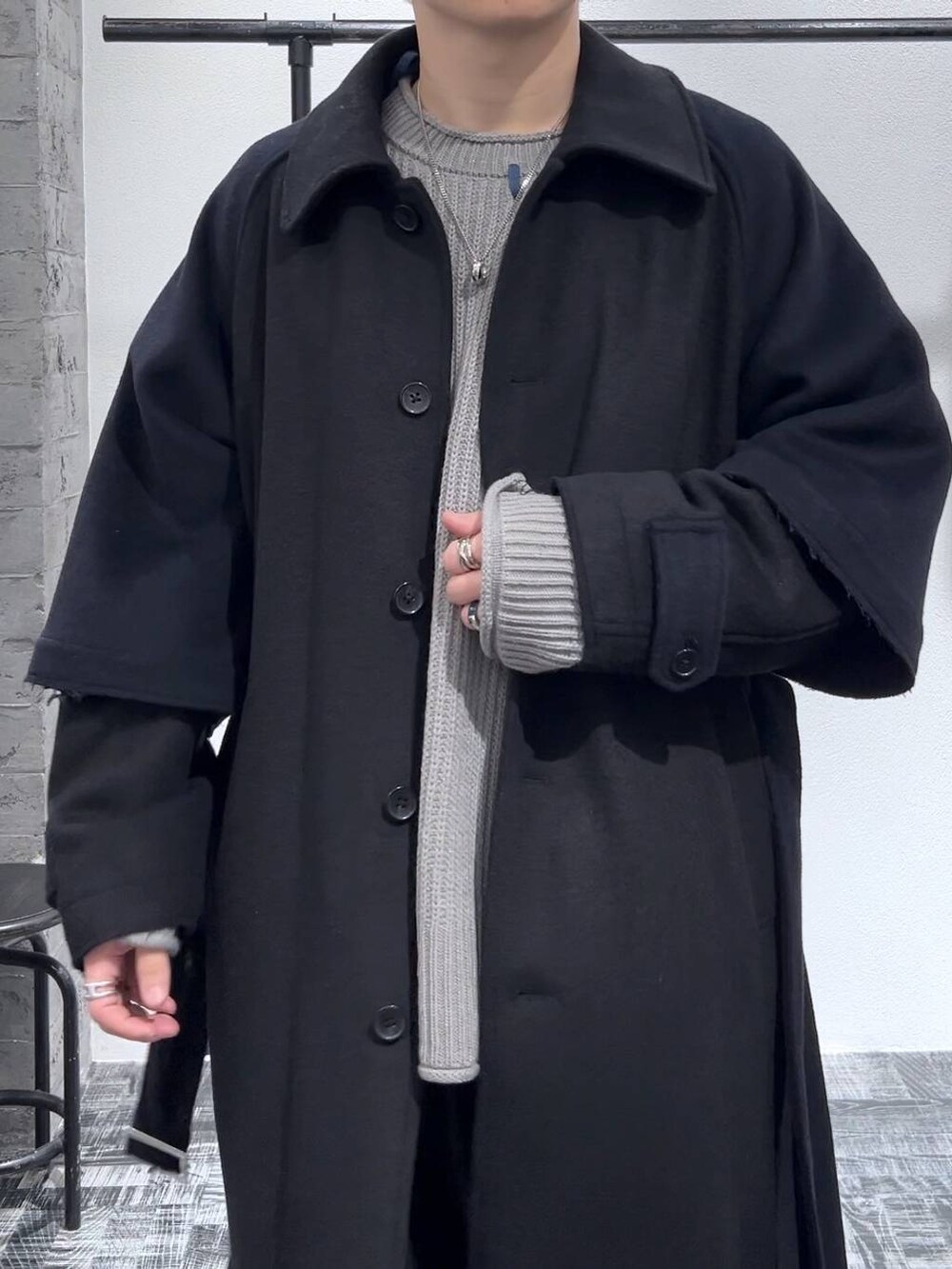 ブラック系のカーゴパンツ、ブラック系のトレンチコート、グレー系のニット/セーターを着用したメンズの冬コーディネートの5枚目の写真