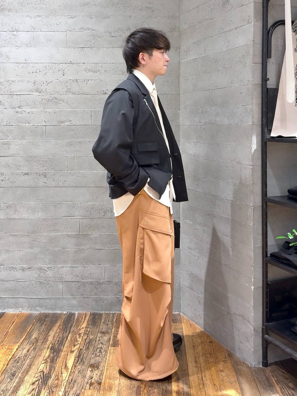 ブラック系のスニーカー、ブラック系のハンドバッグ、ブラック系のテーラードジャケットを着用したメンズの冬コーディネートの2枚目の写真