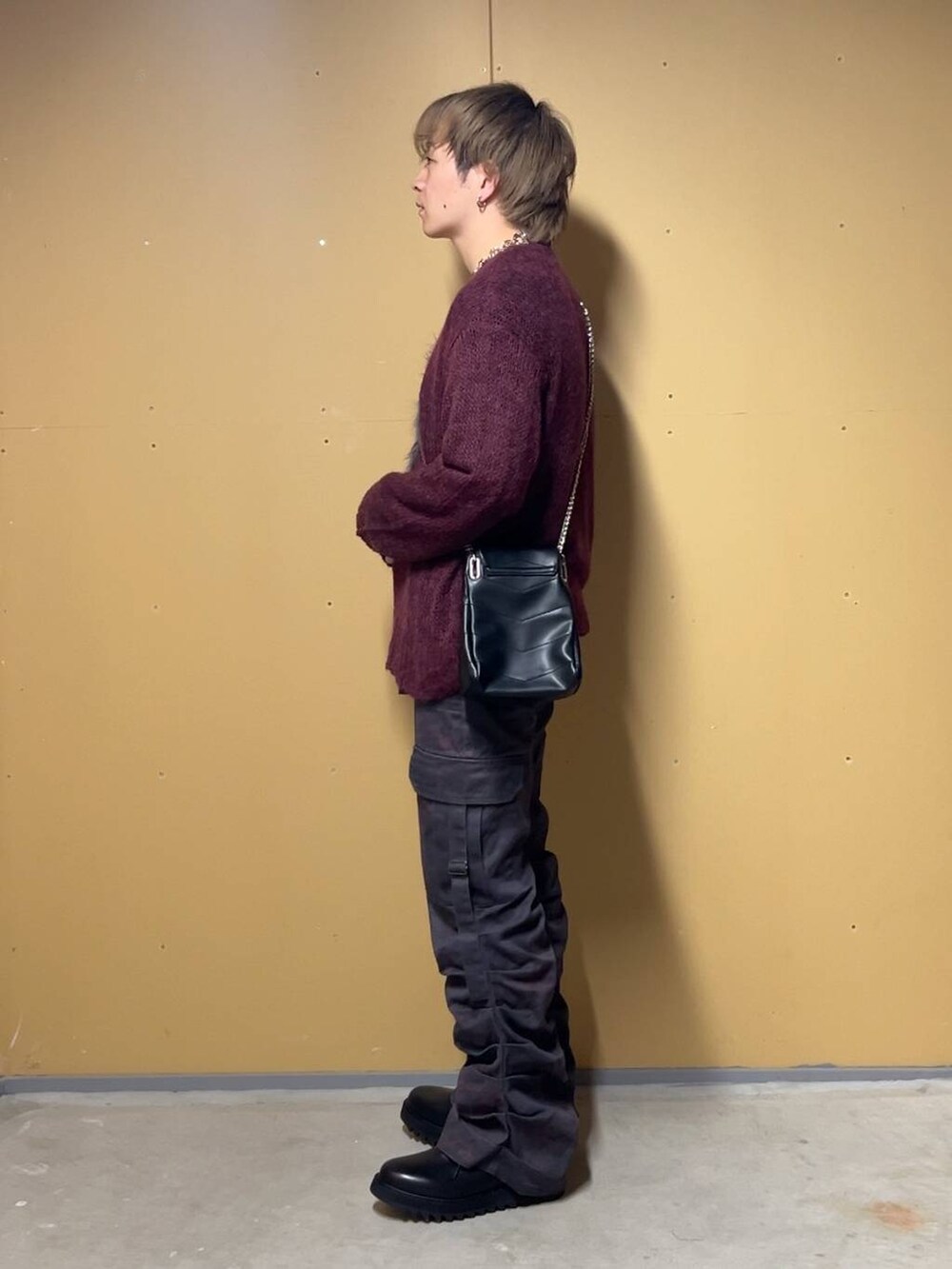 ブラック系のドレスシューズ、ブラック系のショルダーバッグ、レッド系のニット/セーターを着用したメンズの春コーディネートの4枚目の写真