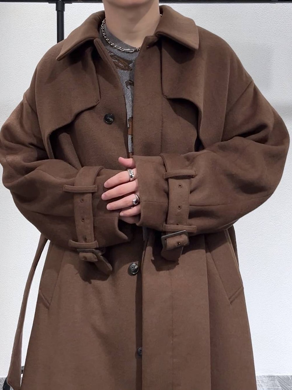 ブルー系のデニムパンツ、グレー系のニット/セーター、ブラウン系のステンカラーコートを着用したメンズの冬コーディネートの5枚目の写真