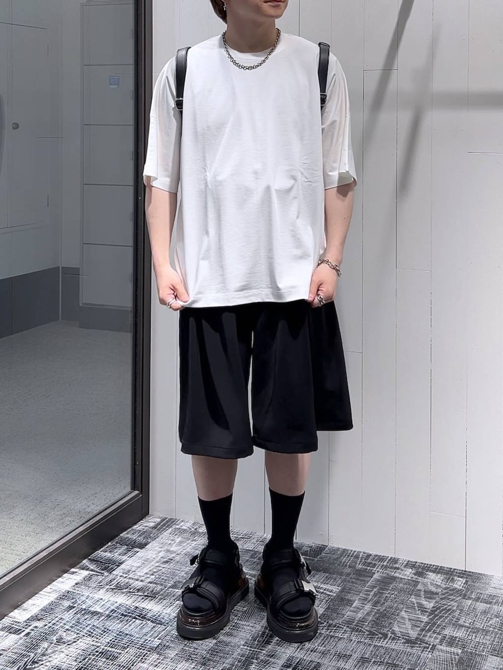 ブラック系のその他パンツ、ホワイト系のTシャツ/カットソー、ブラック系のサンダルを着用したメンズの春コーディネートの2枚目の写真