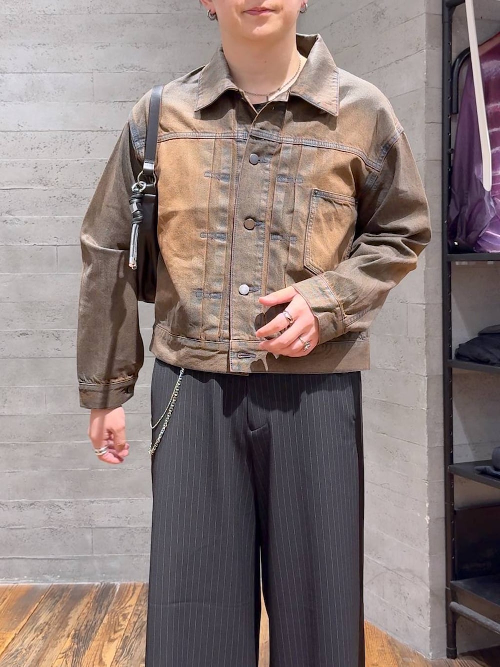 ブラウン系のデニムジャケット、ブラック系のスラックス、ブラック系のTシャツ/カットソーを着用したメンズの夏コーディネートの5枚目の写真