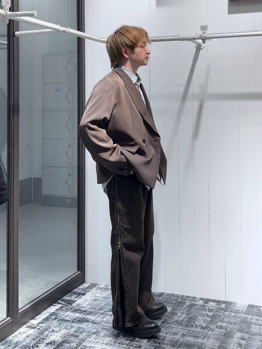 オレンジ系のデニムパンツ、ブラウン系のテーラードジャケット、ブラック系のドレスシューズを着用したメンズの春コーディネートの2枚目の写真