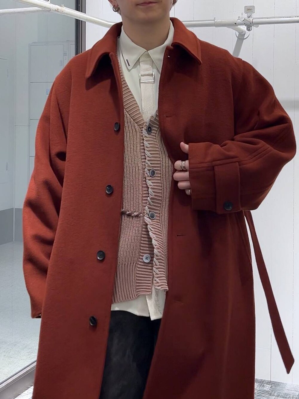 オレンジ系のステンカラーコート、グレー系のカーゴパンツ、ピンク系のカーディガン/ボレロを着用したメンズの冬コーディネートの5枚目の写真