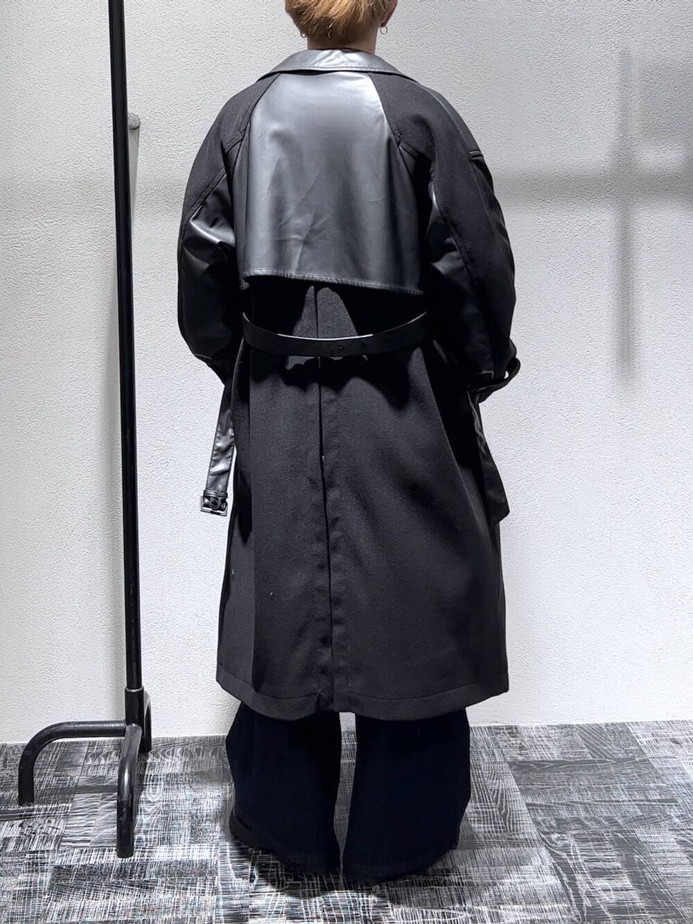 ブルー系のデニムパンツ、ブラック系のトレンチコート、ブラック系のショルダーバッグを着用したメンズの秋コーディネートの4枚目の写真