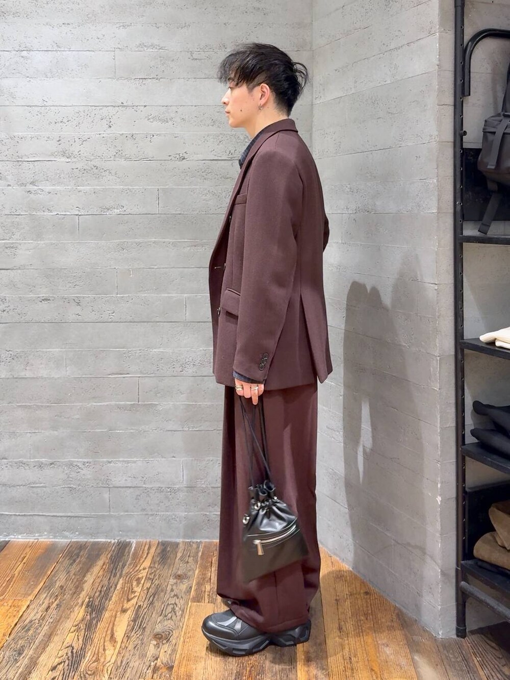 ブラック系のスニーカー、ブラック系のショルダーバッグ、レッド系のスラックスを着用したメンズの秋コーディネートの4枚目の写真