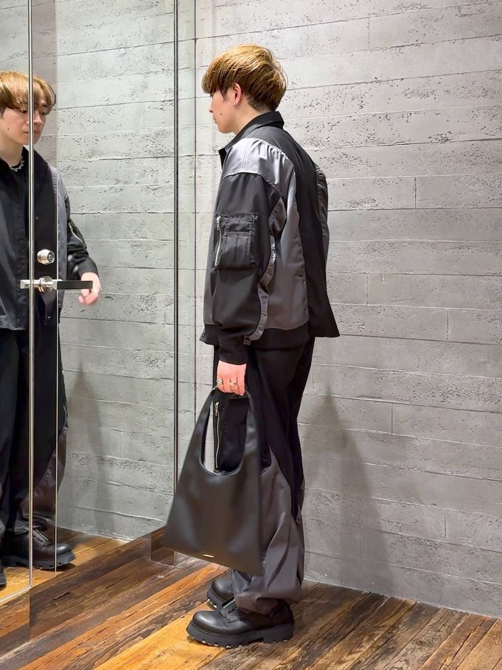 ブラック系のトートバッグ、ブラック系のTシャツ/カットソー、ブラック系のドレスシューズを着用したメンズの春コーディネートの4枚目の写真