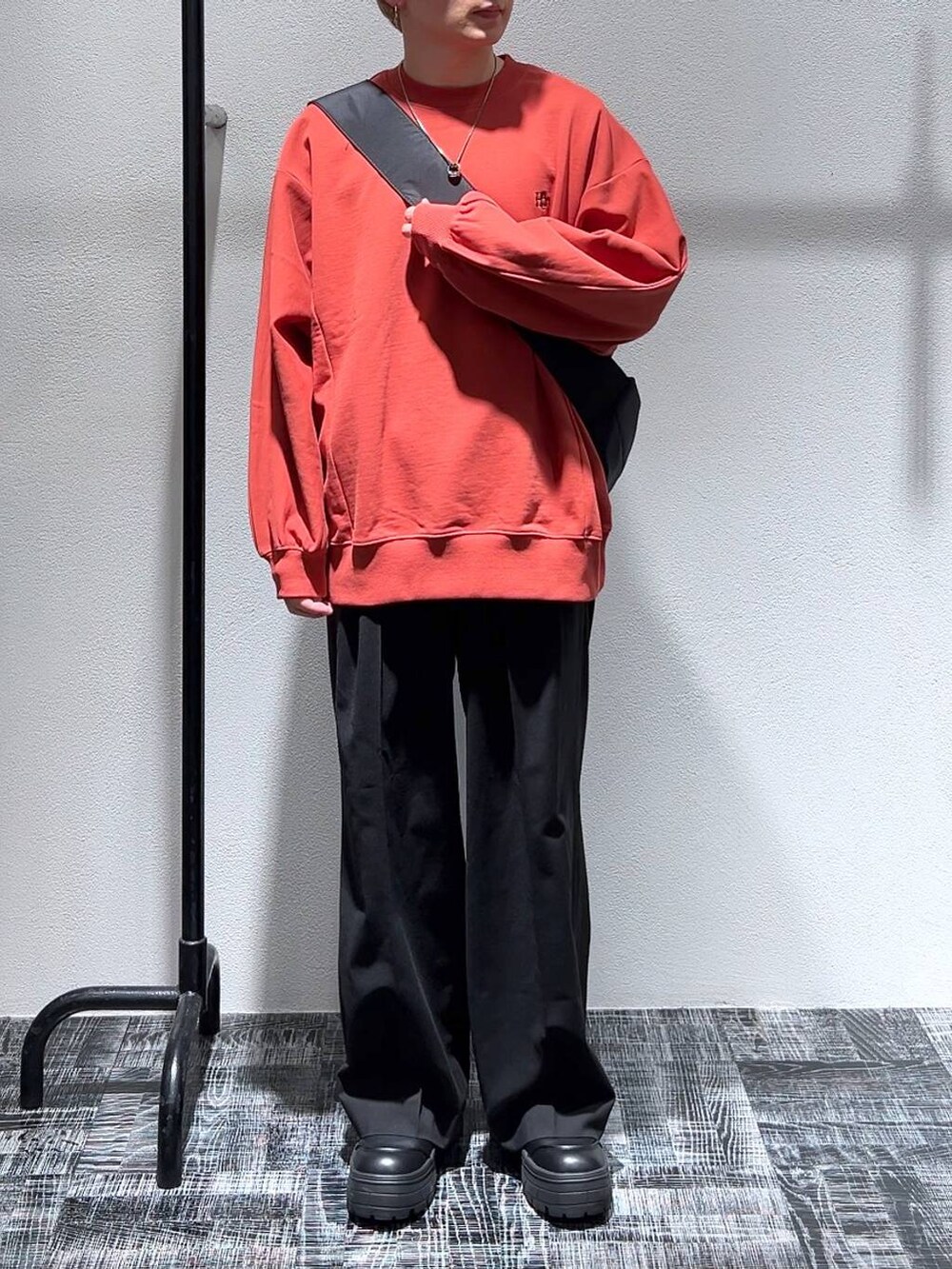 ブラック系のショルダーバッグ、オレンジ系のスウェット、ブラック系のブーツを着用したメンズの冬コーディネートの3枚目の写真