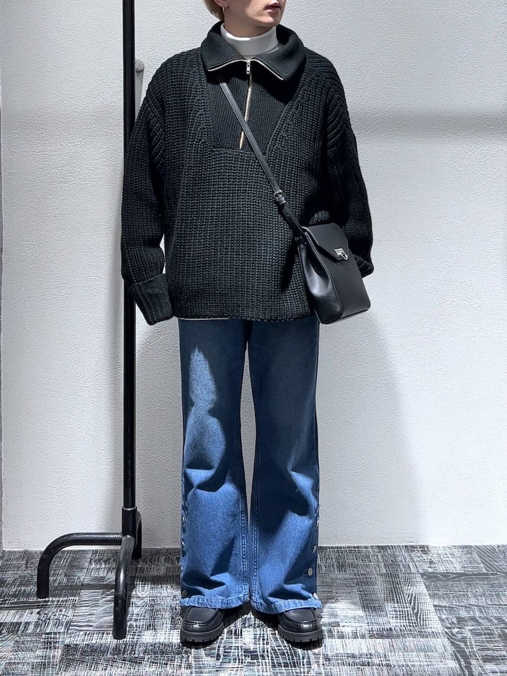 ブルー系のデニムパンツ、ブラック系のショルダーバッグ、ブラック系のドレスシューズを着用したメンズの冬コーディネートの2枚目の写真