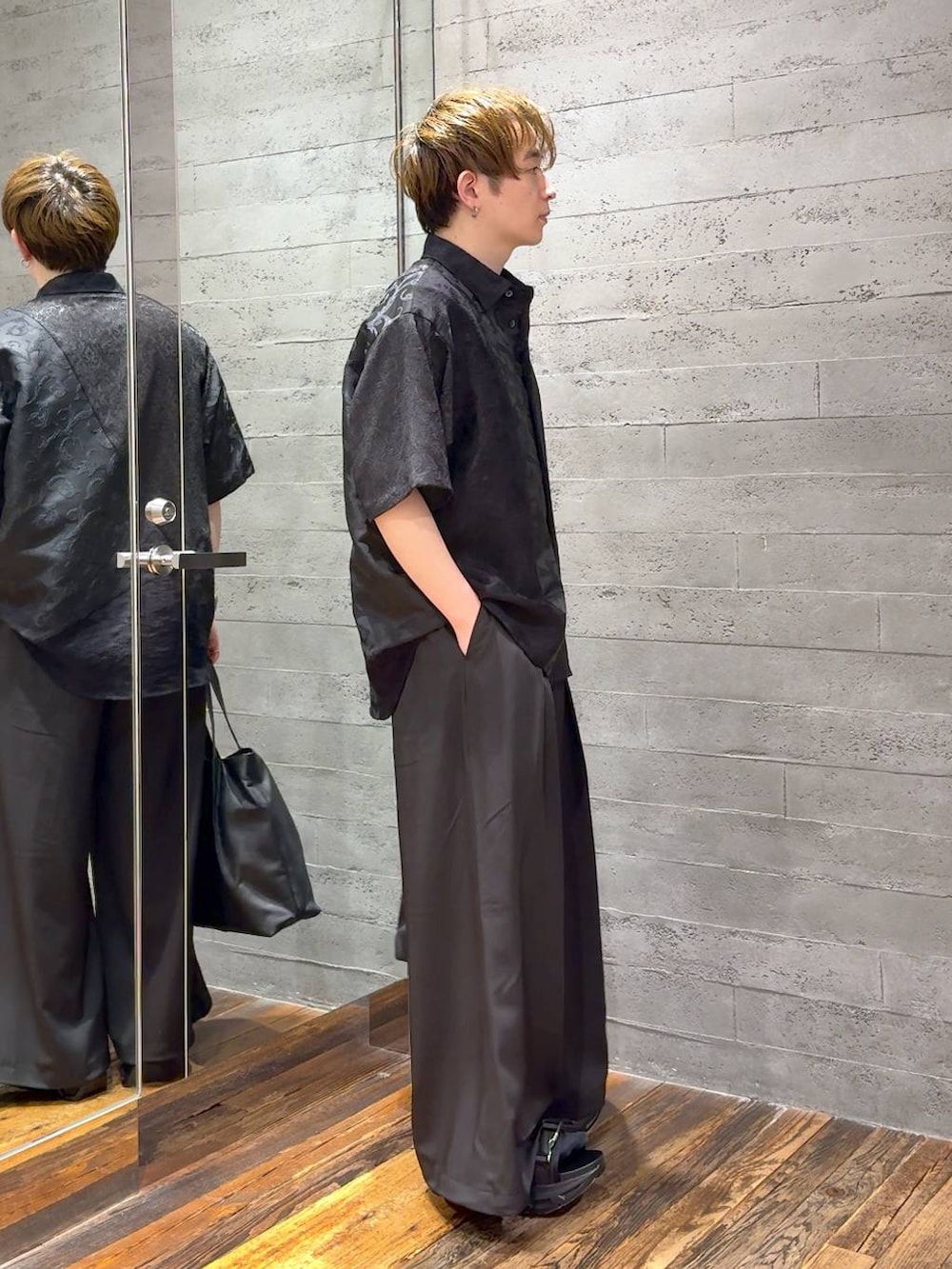 ブラック系のサンダル、ブラック系のTシャツ/カットソー、ブラック系のトートバッグを着用したメンズの春コーディネートの2枚目の写真