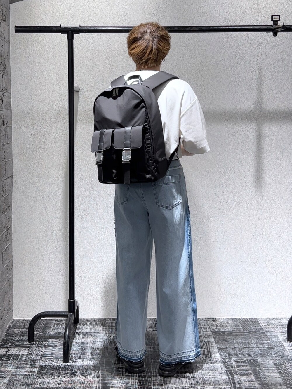 ホワイト系のTシャツ/カットソー、ブルー系のデニムパンツ、ブラック系のバックパック/リュックを着用したメンズの春コーディネートの3枚目の写真