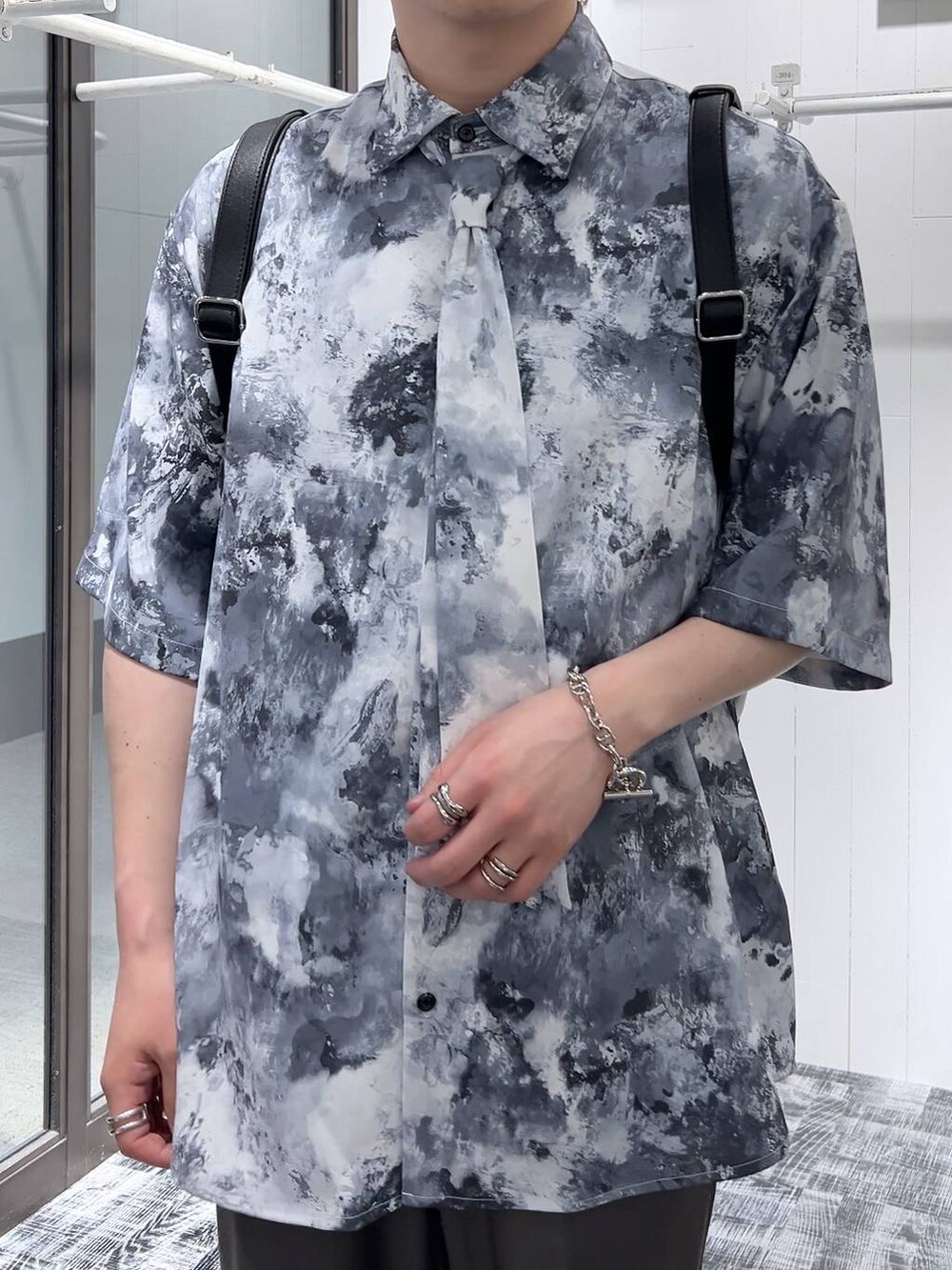 ブラック系のドレスシューズ、ブラック系のショルダーバッグ、グレー系のスラックスを着用したメンズの春コーディネートの5枚目の写真