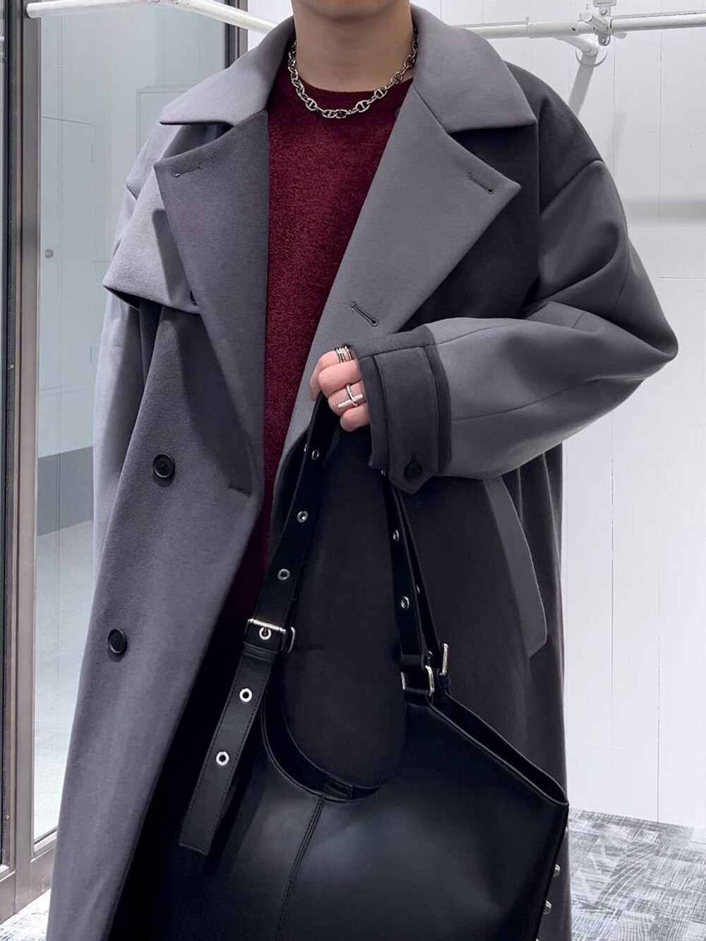 グレー系のトレンチコート、ブルー系のデニムパンツ、レッド系のニット/セーターを着用したメンズの秋コーディネートの4枚目の写真