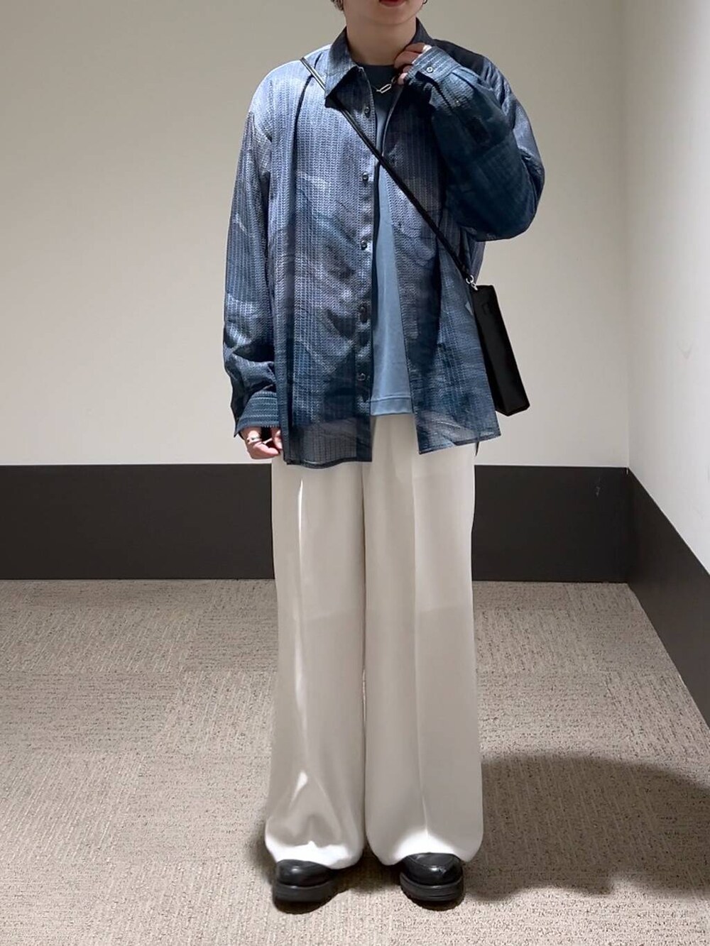 ホワイト系のスラックス、ブルー系のTシャツ/カットソー、ブラック系のショルダーバッグを着用したメンズの冬コーディネートの2枚目の写真