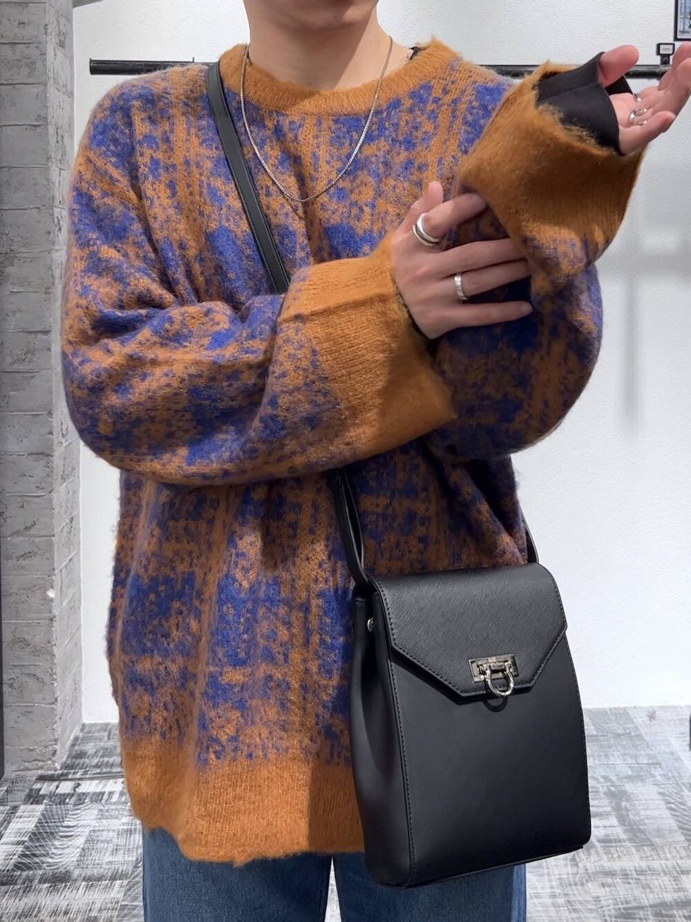 ブルー系のデニムパンツ、ブラック系のショルダーバッグ、オレンジ系のニット/セーターを着用したメンズの秋コーディネートの3枚目の写真