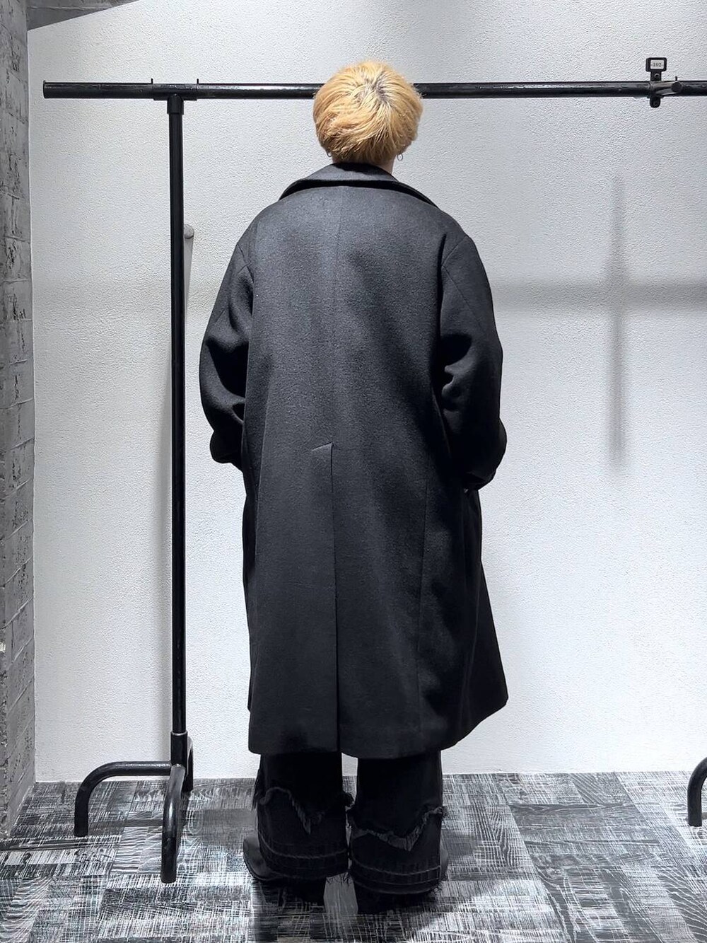 ブラック系のドレスシューズ、ブラック系のステンカラーコート、ブラック系のショルダーバッグを着用したメンズの冬コーディネートの3枚目の写真